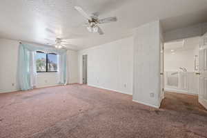 Carpeted spare room with a textured ceiling and ceiling fan