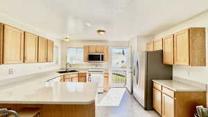 Kitchen featuring kitchen peninsula, appliances with stainless steel finishes, plenty of natural light, and sink