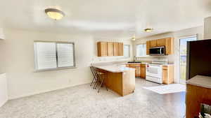 Kitchen with sink, appliances with stainless steel finishes, kitchen peninsula, and a breakfast bar