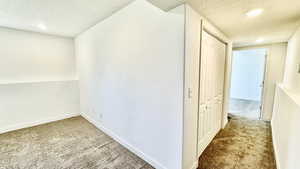 Corridor with carpet floors and a textured ceiling