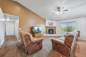 Living room featuring light wood-type flooring, vaulted ceiling, and ceiling fan