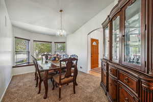 Dining space featuring an inviting chandelier and light carpet