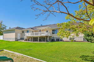 Back of property featuring a wooden deck, a lawn, and central air condition unit