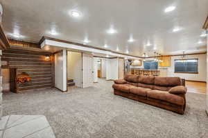 Living room with wood walls, carpet flooring, and ornamental molding