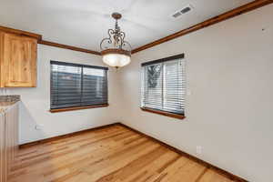 Unfurnished dining area featuring light wood-type flooring, crown molding, and a healthy amount of sunlight