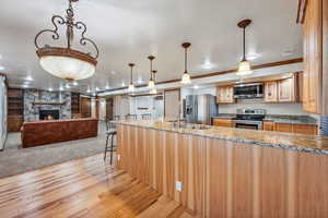 Kitchen with light stone countertops, light hardwood / wood-style floors, appliances with stainless steel finishes, and a fireplace