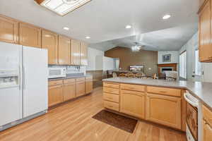 Kitchen with ceiling fan, light brown cabinets, lofted ceiling, white appliances, and light hardwood / wood-style flooring