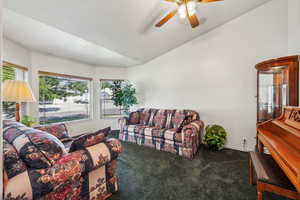 Living room featuring ceiling fan, carpet flooring, and vaulted ceiling