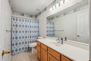 Bathroom with vanity, tile patterned floors, toilet, and a shower with shower curtain