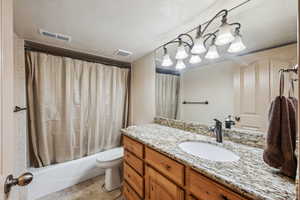 Full bathroom with vanity, toilet, a textured ceiling, and shower / bath combo