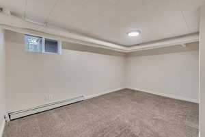 Basement featuring baseboard heating and carpet floors