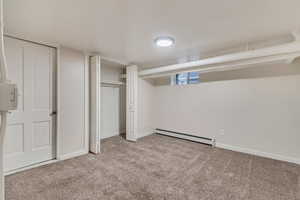 Unfurnished bedroom with light carpet and a baseboard heating unit