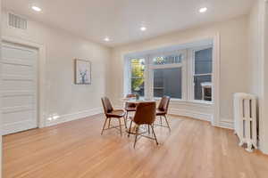 Dining area featuring light hardwood / wood-style flooring and radiator heating unit