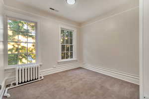 Unfurnished room with carpet floors, crown molding, and radiator heating unit