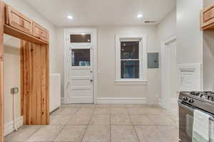 Interior space with radiator, electric panel, and light tile patterned floors