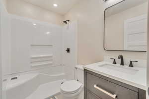 Bathroom featuring walk in shower, vanity, and toilet