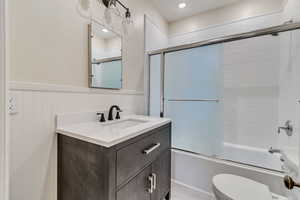 Full bathroom featuring bath / shower combo with glass door, vanity, and toilet