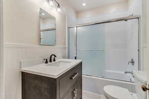 Full bathroom featuring enclosed tub / shower combo, vanity, and toilet