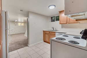 Kitchen with white appliances, light tile patterned flooring, and sink