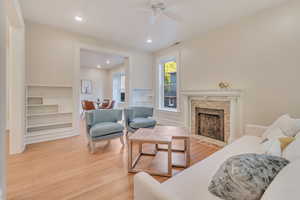 Living room with ceiling fan, a stone fireplace, and hardwood / wood-style floors