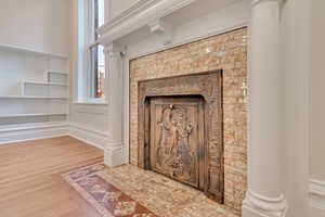 Details with wood-type flooring, decorative columns, and a fireplace