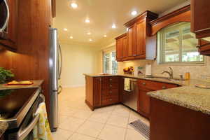 Kitchen with light tile patterned floors, sink, crown molding, kitchen bar, and plenty of cabinets