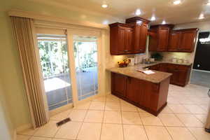 Kitchen with light tile patterned floors, sink, crown molding, kitchen bar, and plenty of cabinets