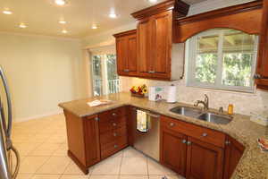 Kitchen with light tile patterned floors, sink, crown molding, kitchen bar, and plenty of cabinets