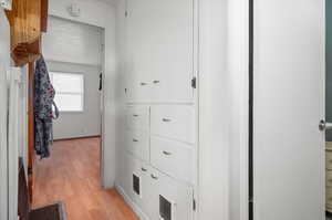 Hallway with a textured ceiling and light hardwood / wood-style floors