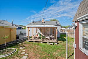 Rear view of house featuring a lawn and a large covered deck with private bedroom entrance