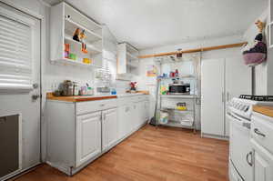 Kitchen featuring light hardwood / wood-style floors, white cabinets, white range, wood counters, and sink