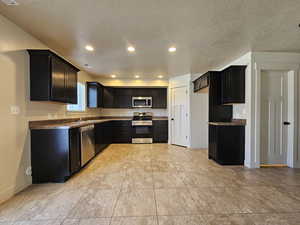 Kitchen with appliances with stainless steel finishes, a textured ceiling, and sink