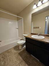 Full bathroom featuring vanity, a textured ceiling, shower / washtub combination, tile patterned floors, and toilet