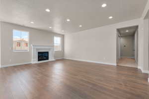 Unfurnished living room featuring dark wood-type flooring and a textured ceiling