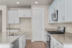 Kitchen featuring light hardwood / wood-style flooring, white cabinetry, stainless steel appliances, and sink