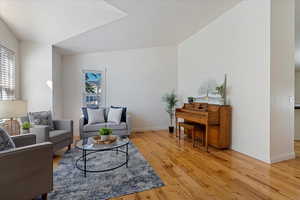 Living room with light hardwood / wood-style flooring, vaulted ceiling, and plenty of natural light