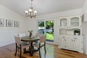 Dining room with light wood-type flooring, a chandelier, and vaulted ceiling