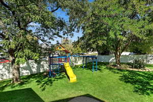 View of jungle gym featuring a lawn and a water view