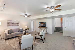 Carpeted living room featuring ceiling fan