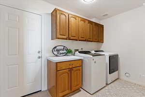 Washroom featuring cabinets, light tile patterned flooring, and washing machine and dryer