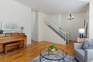 Living room featuring a notable chandelier, light hardwood / wood-style floors, and a textured ceiling