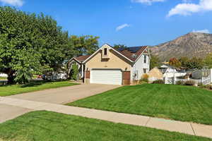 View of front of home with a mountain view and a front lawn