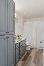 Bathroom with walk in shower, vanity, toilet, and hardwood / wood-style flooring