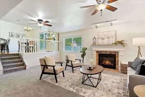 Carpeted living room with ceiling fan, a textured ceiling, a fireplace, and rail lighting