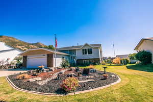 View of front of house with a garage, a mountain view, and a front yard