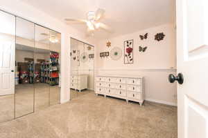 Carpeted bedroom featuring ceiling fan and multiple closets