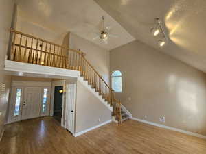 Entrance foyer featuring rail lighting, high vaulted ceiling, a textured ceiling, ceiling fan, and hardwood / wood-style floors