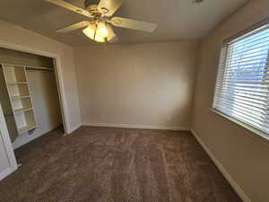 down stairs bedroom with ceiling fan, a closet, multiple windows, and new carpet