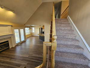 Staircase with a tile fireplace, high vaulted ceiling, and NEW flooring