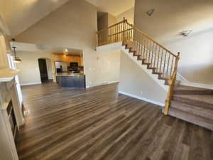 Unfurnished living room with high vaulted ceiling, a textured ceiling, and new dark wood-type flooring